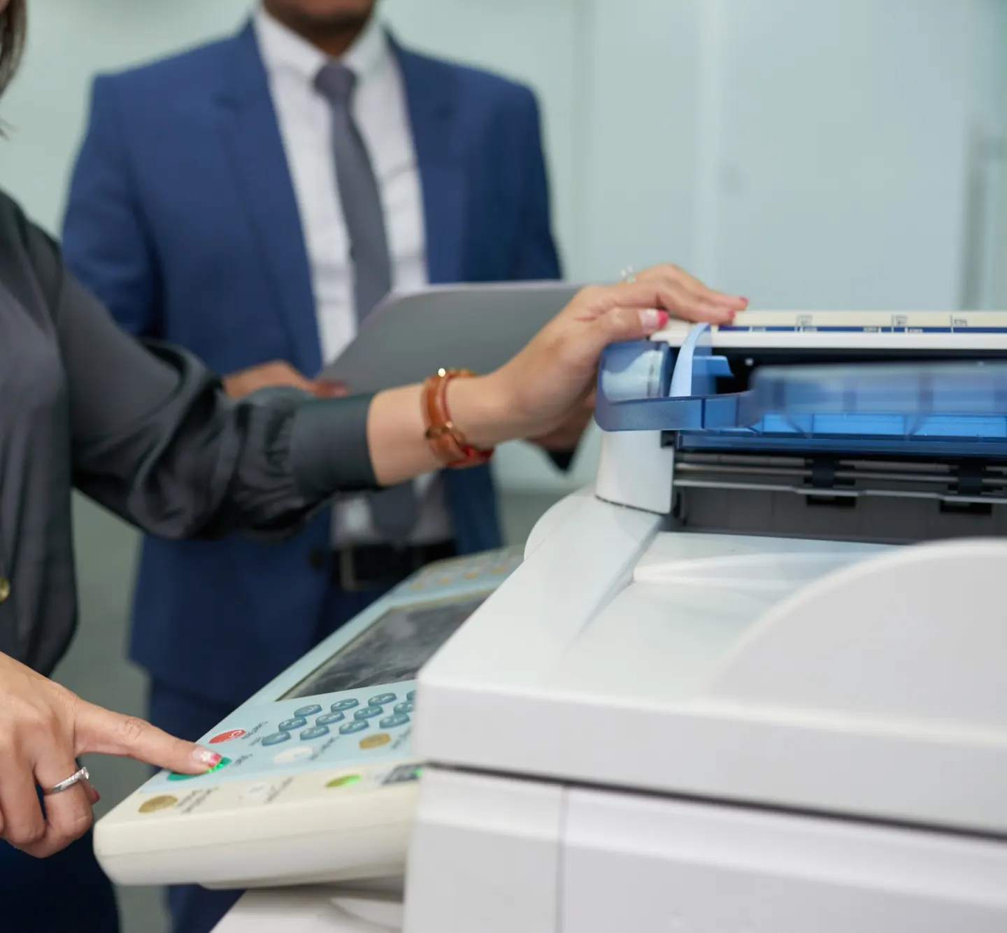 Office assistant using a multifunction (MF) printer while a colleague in a suit looks on